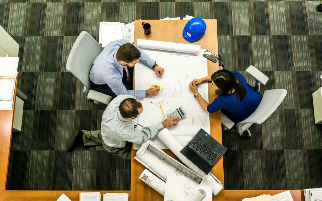 pexels-photo-416405-416405-1 Top view of a team working on construction plans in an office setting.